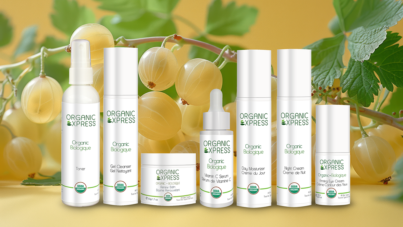 Organic Express Collection of seven products on a flat surface with Amla berries on a branch in the background.