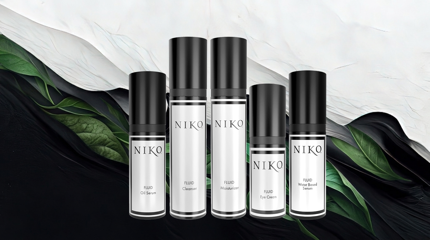 Set of NIKO Fluid line skincare products with black and white packaging on a dark background with green leaves.